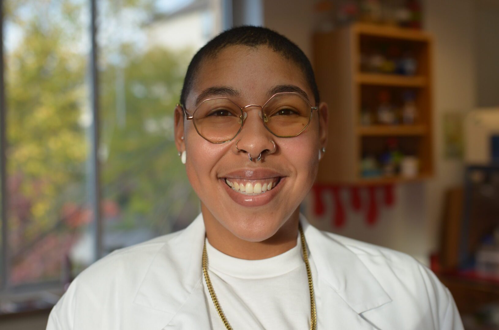 A woman in white shirt and glasses smiling.