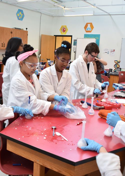 A group of people in lab coats and gloves working on something.