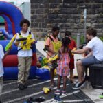 A Group Of People Standing Around With Some Toys.