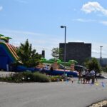 A Group Of People Standing Around An Inflatable Slide.
