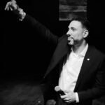 A Man In A Suit And Tie Holding His Arm Up.