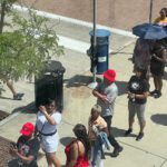 A Group Of People Standing On The Sidewalk.